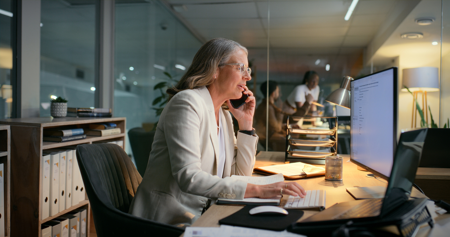 Possible AI Fraud. Mature woman on phone call looking at computer with financial data.