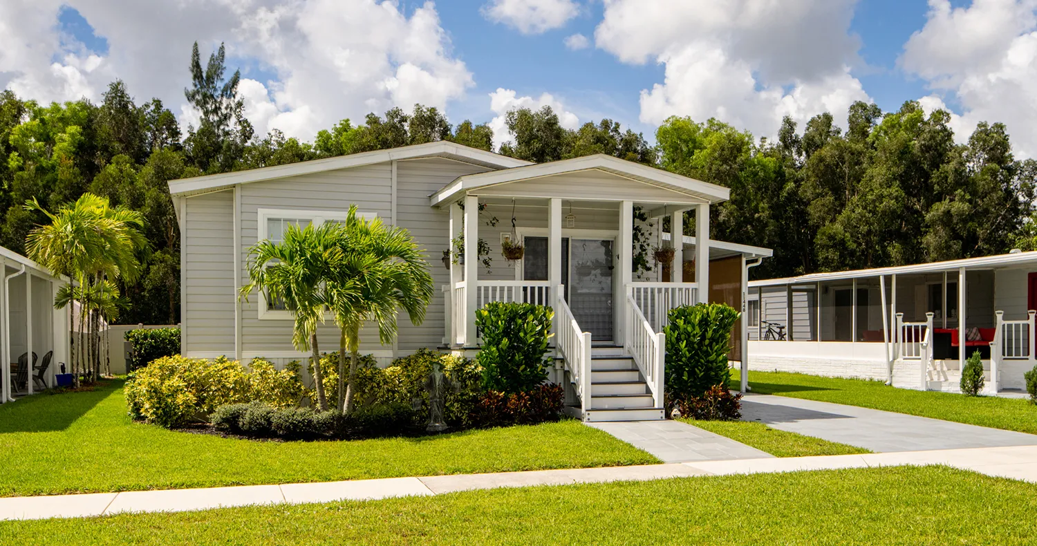A manufactured home in a manufactured home community with green grass and blue skies.