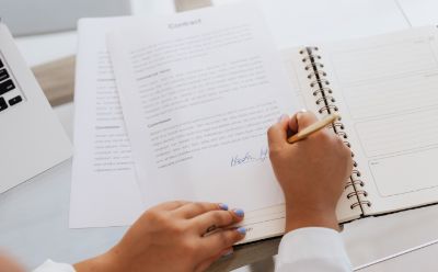 A person signing a written contract with a pen. 