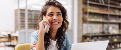 woman holding a cell phone, using a laptop for banking 