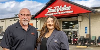 A True Value Fremont Plaza Hardware owner stands with a Community West Bank representative outside the Stockton store, highlighting local business support. 
