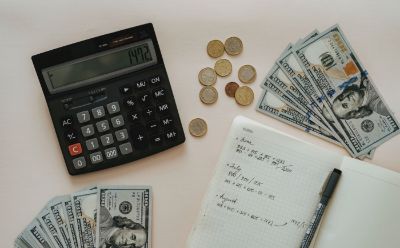 A calculator, money, and a journal on a table. 